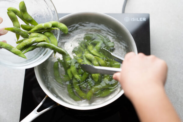 adding frozen edamame to boiling water