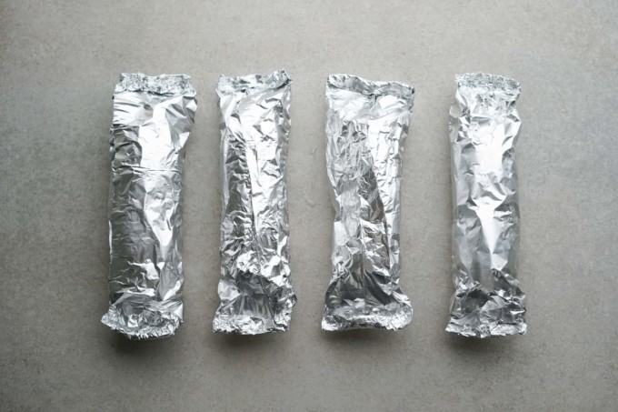 four ears of corn wrapped in foil
