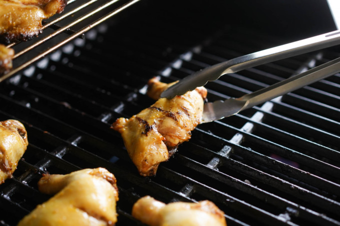 moving chicken with tongs on the grill