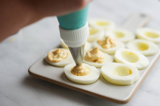 piping yolk mixture into eggs