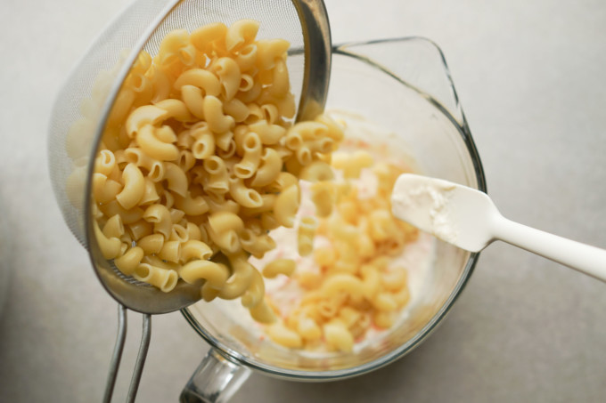 pouring macaroni into the dressing