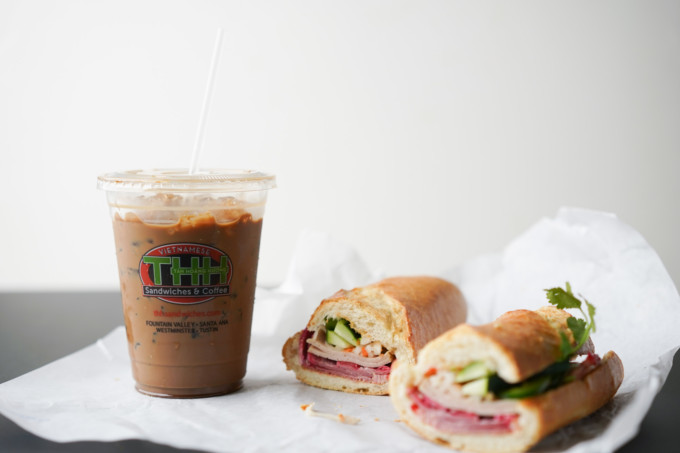 takeout cup of Viet coffee and two banh mi