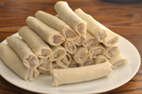 plate of wrapped uncooked egg rolls